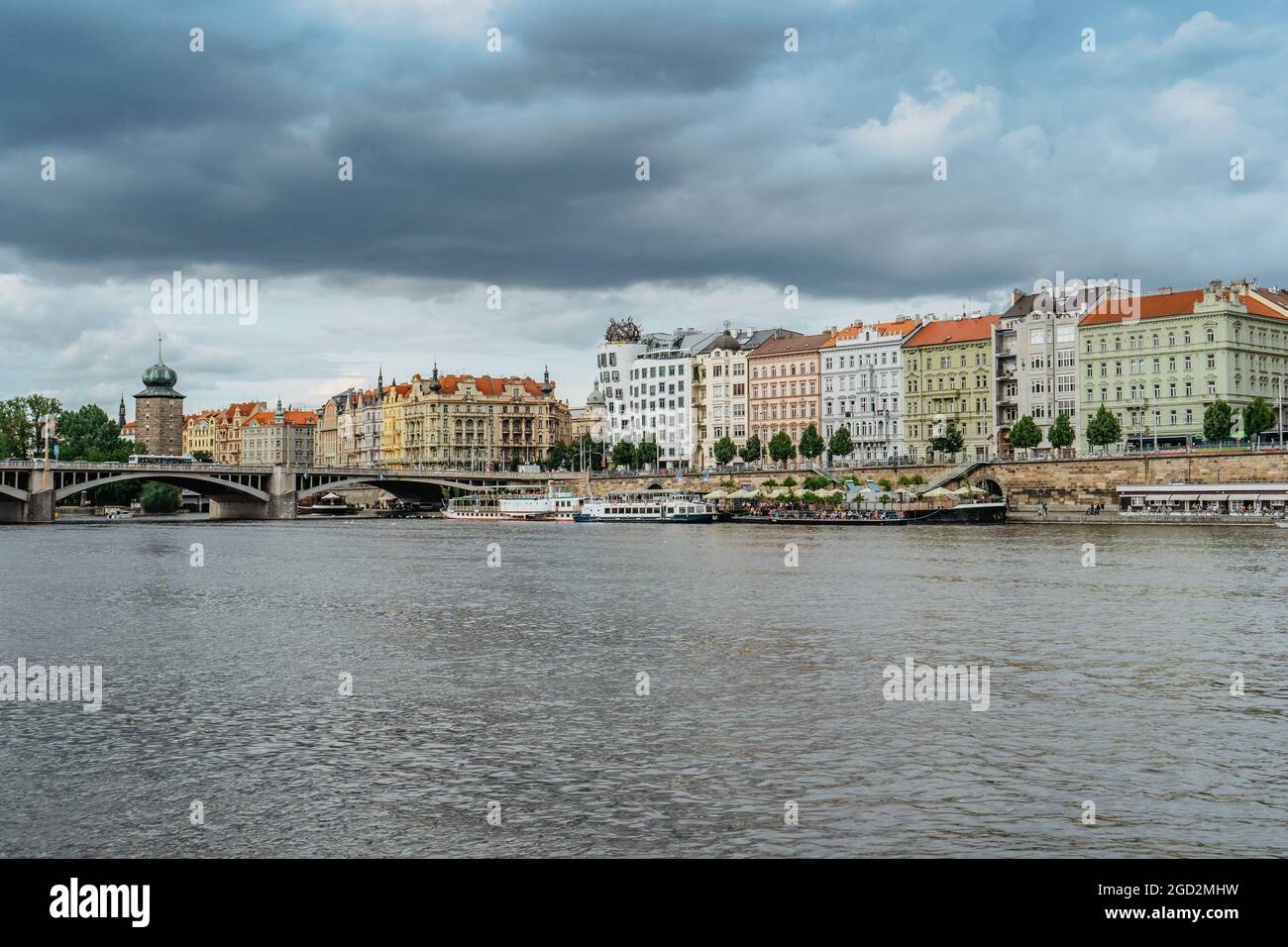 Prague, République Tchèque. Vue imprenable sur la célèbre Dancing House et Rasin Embankment. Bâtiments colorés au bord de la rivière, pont sur la Vltava, bateaux. Banque D'Images