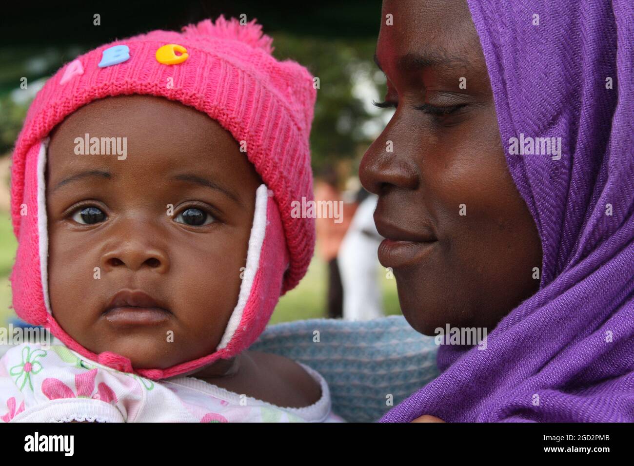 Une femme dans un foulard violet regarde avec amour sa fille Angel (Tanzanie) ca. 4 mars 2014 Banque D'Images