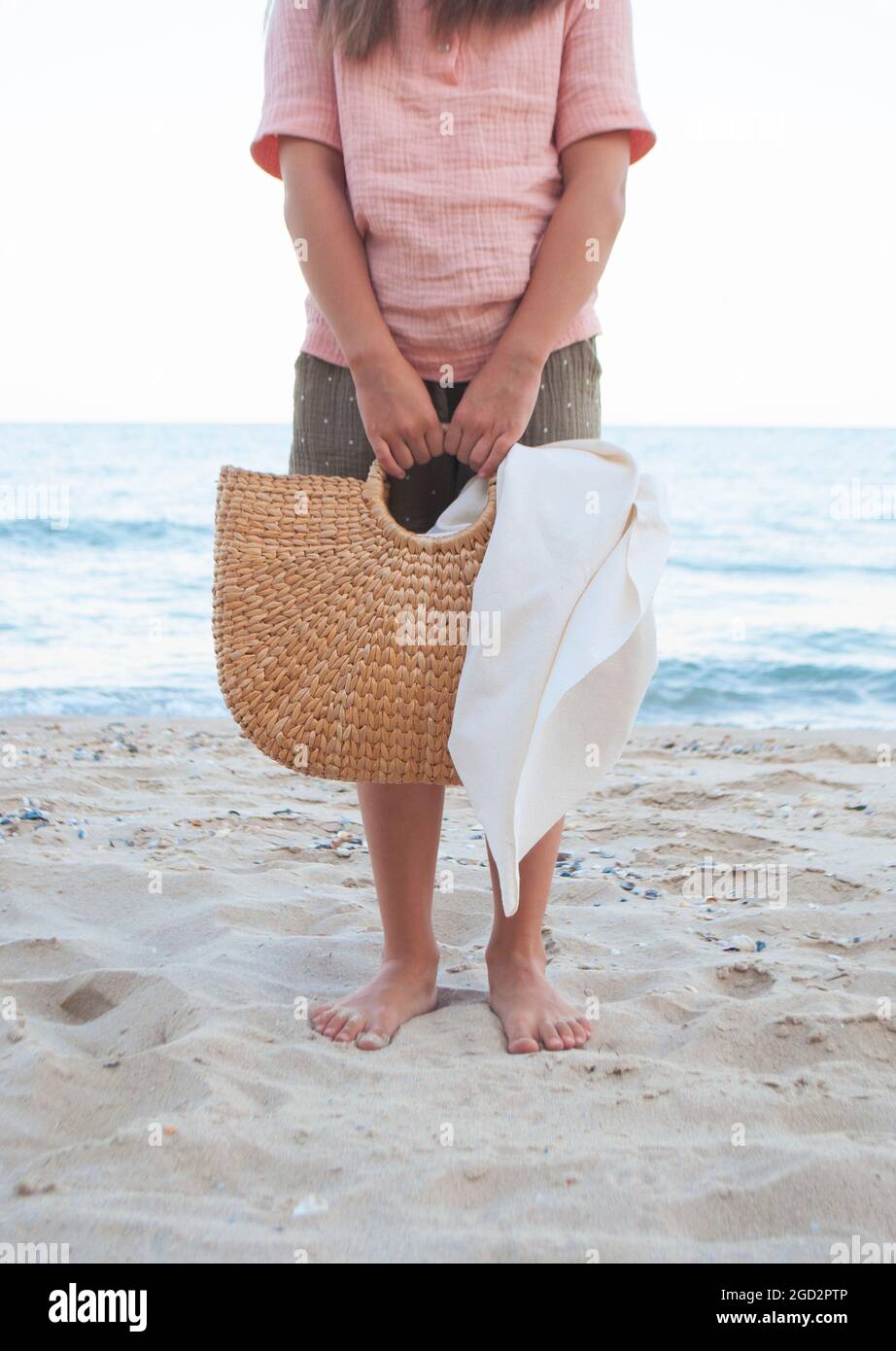 Une jeune fille transportant un sac de paille à la plage en été Photo Stock  - Alamy