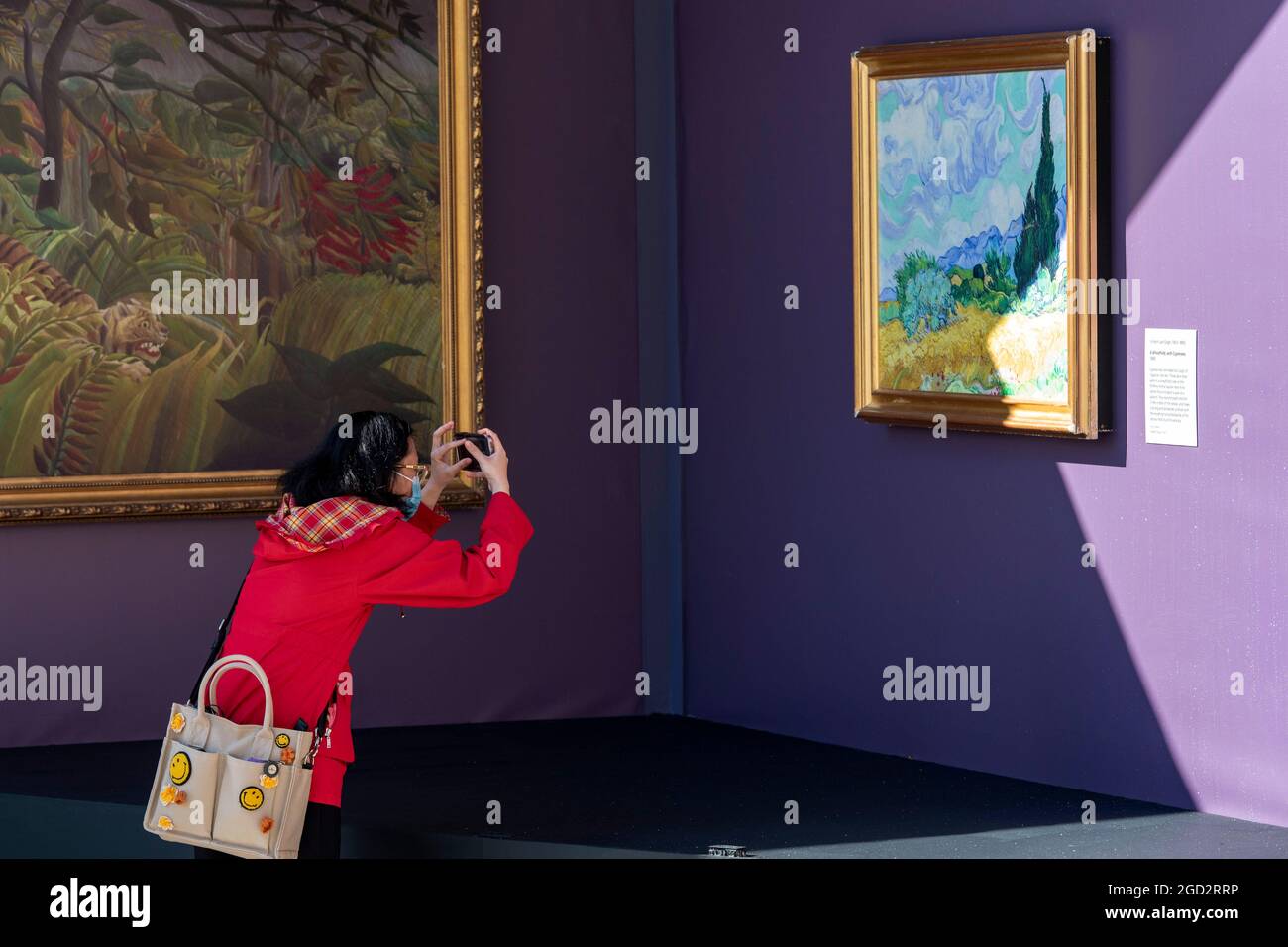 Londres, Royaume-Uni. 10 août 2021. Une femme prend la photo d'un champ de blé avec Cypress par l'artiste Vincent van Gogh dans une galerie pop-up en plein air présentant plus de 20 reproductions de grands chefs-d'œuvre populaires de la National Gallery ainsi que Sketch on the Square qui apporte l'art en plein air dans le cadre du festival Inside Out, Un mois de séances d'art interactives gratuites à l'extérieur de la Galerie nationale de Trafalgar Square. Crédit : SOPA Images Limited/Alamy Live News Banque D'Images