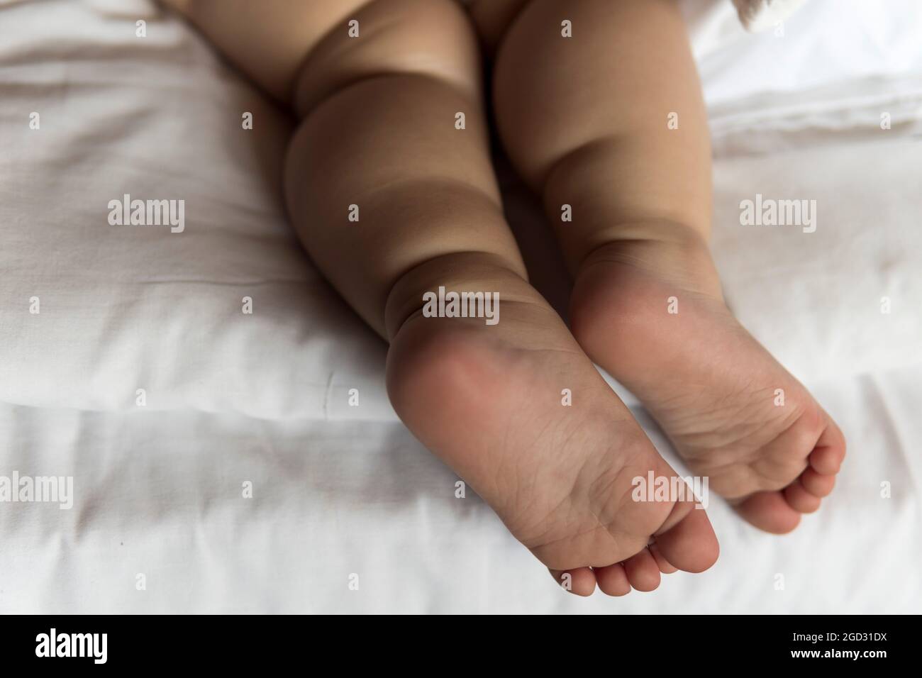 pieds de bébé fille de bébé portant des couches couchés sur le lit blanc à la maison. jambes de plumeuse de dormir un enfant caucasien d'un an. enfant dort dans un lit de bébé. maison Banque D'Images