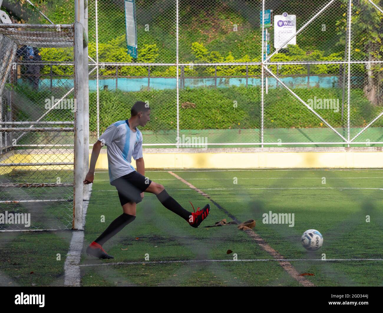 Medellin, Antioquia, Colombie - juillet 30 2021: L'homme latin dans Sportswear est en train de courir un ballon près d'un but de football sur un terrain synthétique vert Banque D'Images