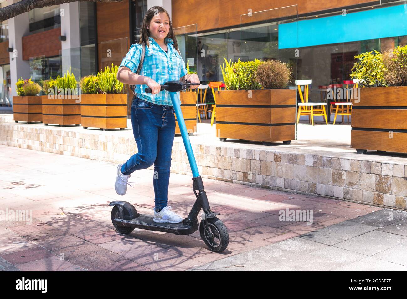 Fille blonde sur le chemin de l'école sur scooter électrique Banque D'Images