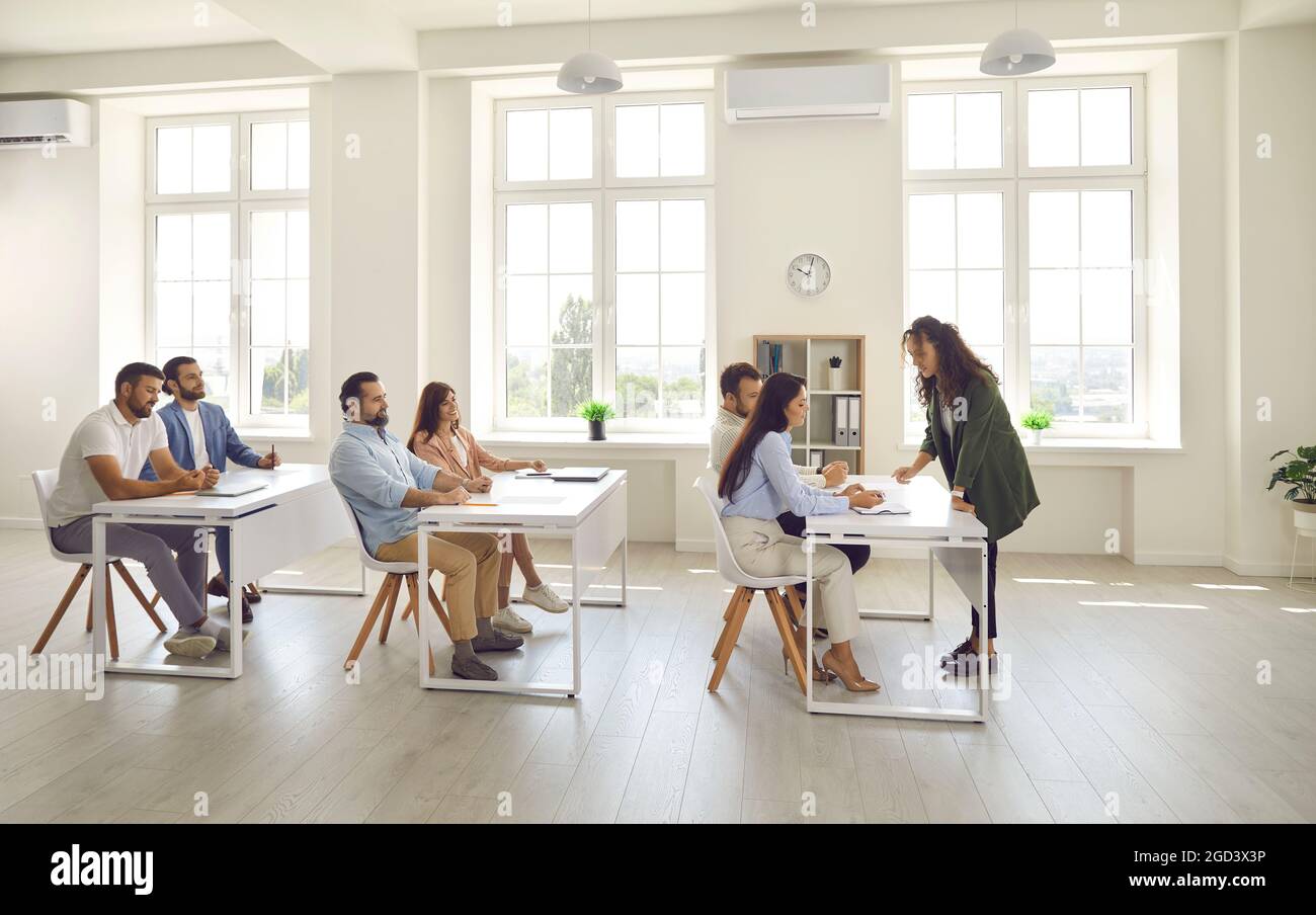 Les personnes qui réussissent, qui sont des étudiants adultes et qui sont assis aux bureaux dans une salle de classe moderne et lumineuse. Banque D'Images