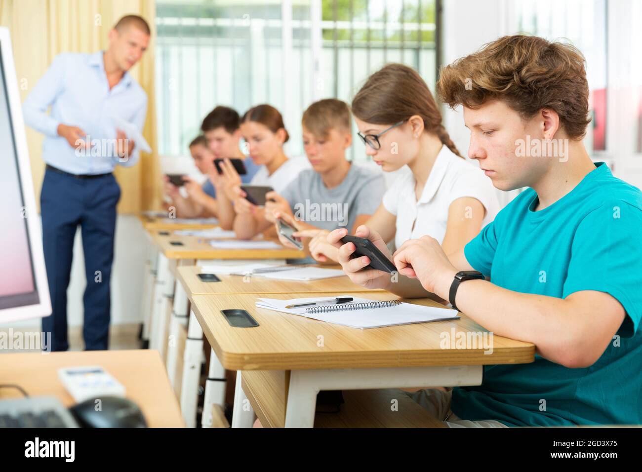 Un adolescent utilisant un téléphone portable lors d'une leçon en classe  Photo Stock - Alamy