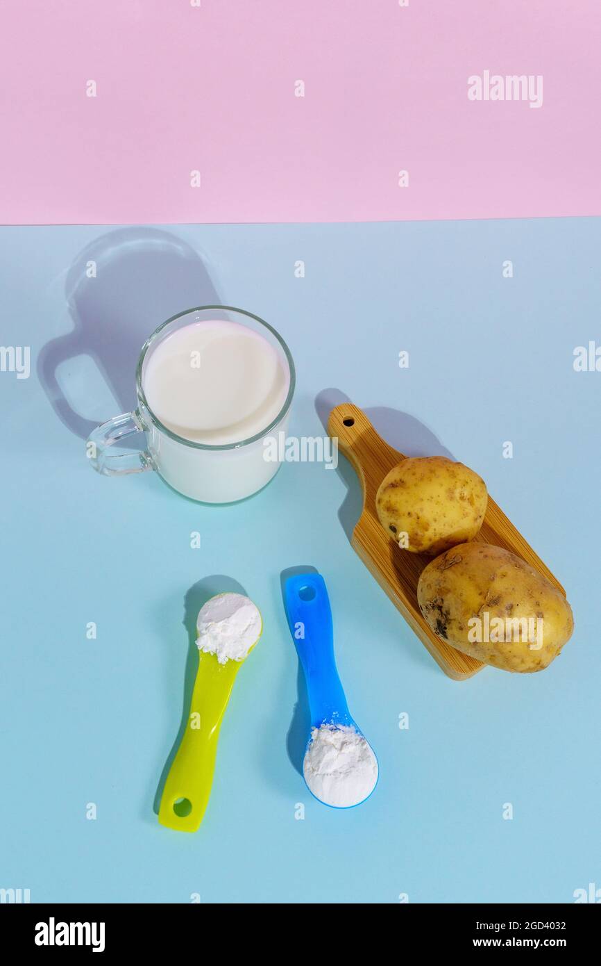 Lait de pomme de terre végétalien en poudre. Un verre de lait sur fond multicolore Banque D'Images