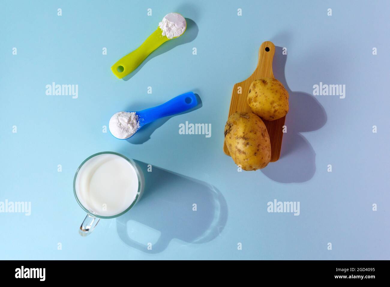 Lait de pomme de terre végétalien en poudre. Un verre de lait sur fond multicolore Banque D'Images