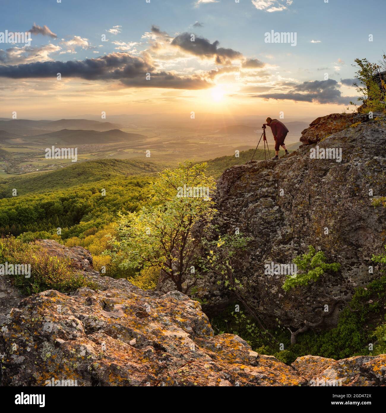 Silouette od photographe dans beau coucher de soleil de montagne avec forêt verte Banque D'Images