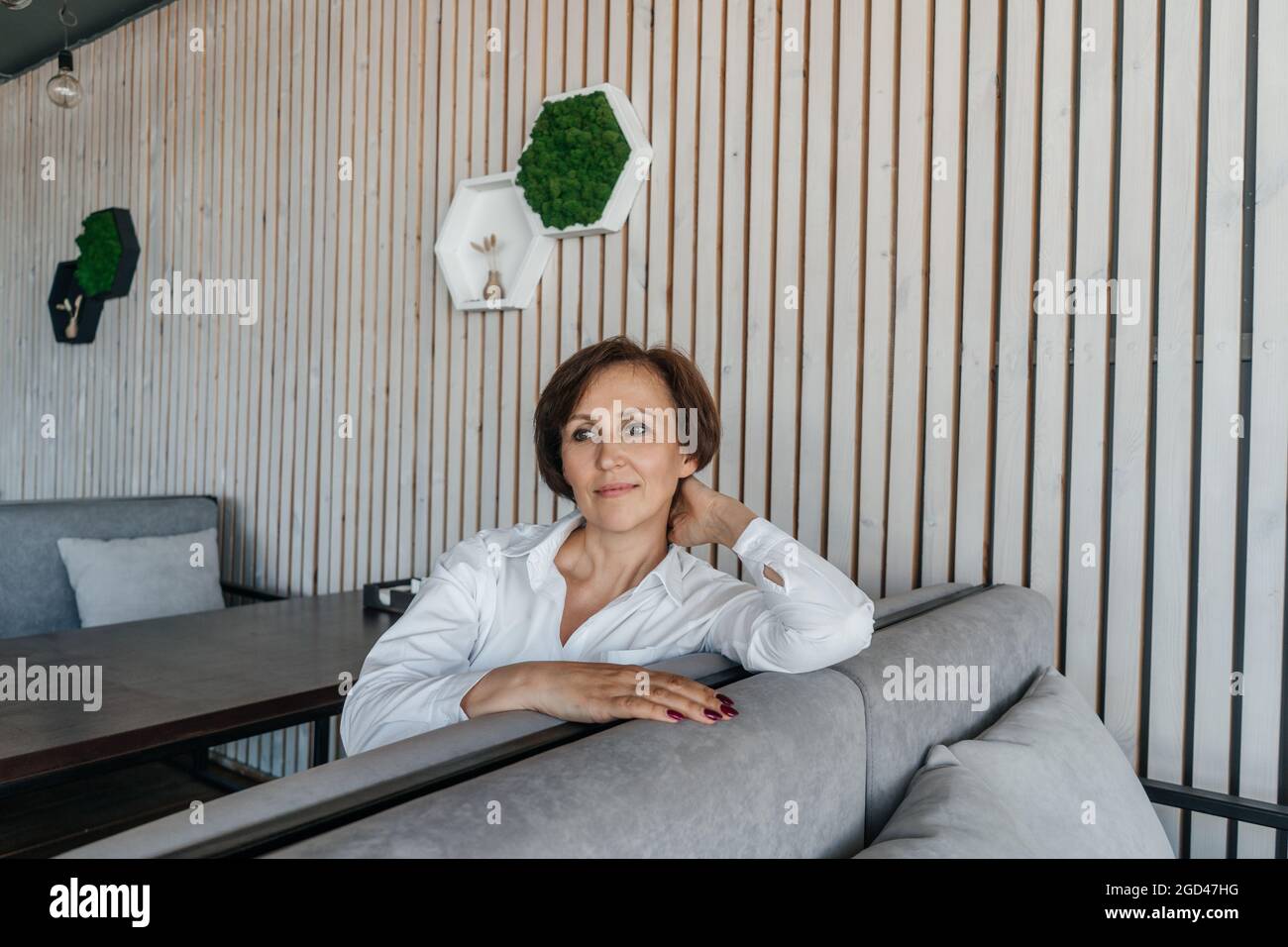 Femme d'affaires senior se reposer dans un café moderne. Mur en bois sur fond. Banque D'Images