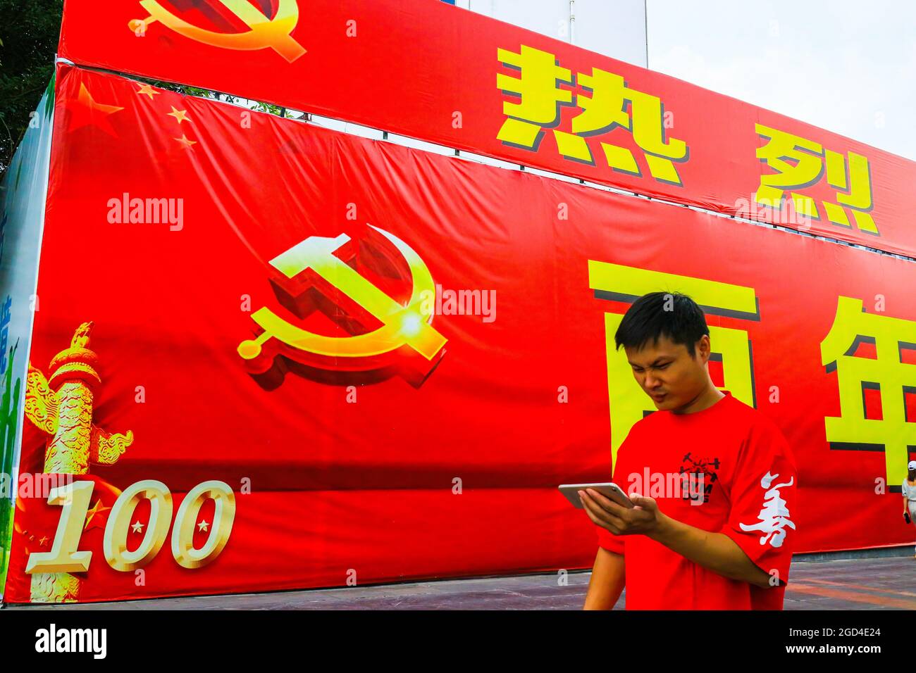 Un homme passe devant une immense bannière commémorant le 100e anniversaire de la fondation du Parti communiste chinois. Une bannière géante célébrant le 100e anniversaire de la fondation du Parti communiste de Chine est exposée sur l'avenue principale de Guilin, en Chine Banque D'Images