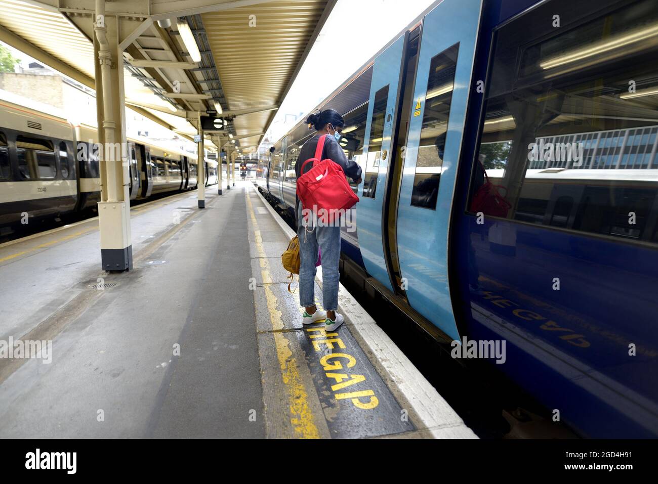 Londres, Angleterre, Royaume-Uni. Gare Victoria : jeune femme sur une plate-forme attendant de monter à bord d'un train Banque D'Images