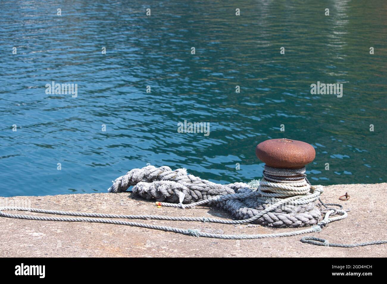 Corde enroulée autour d'un seul bollard d'amarrage côté quai Banque D'Images