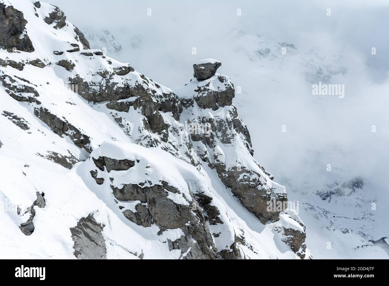 Vue sur une partie de la montagne tandis que le brouillard s'élève et couvre le sommet du Mont Titlis à Engelberg, en Suisse. Sommets enneigés. Banque D'Images