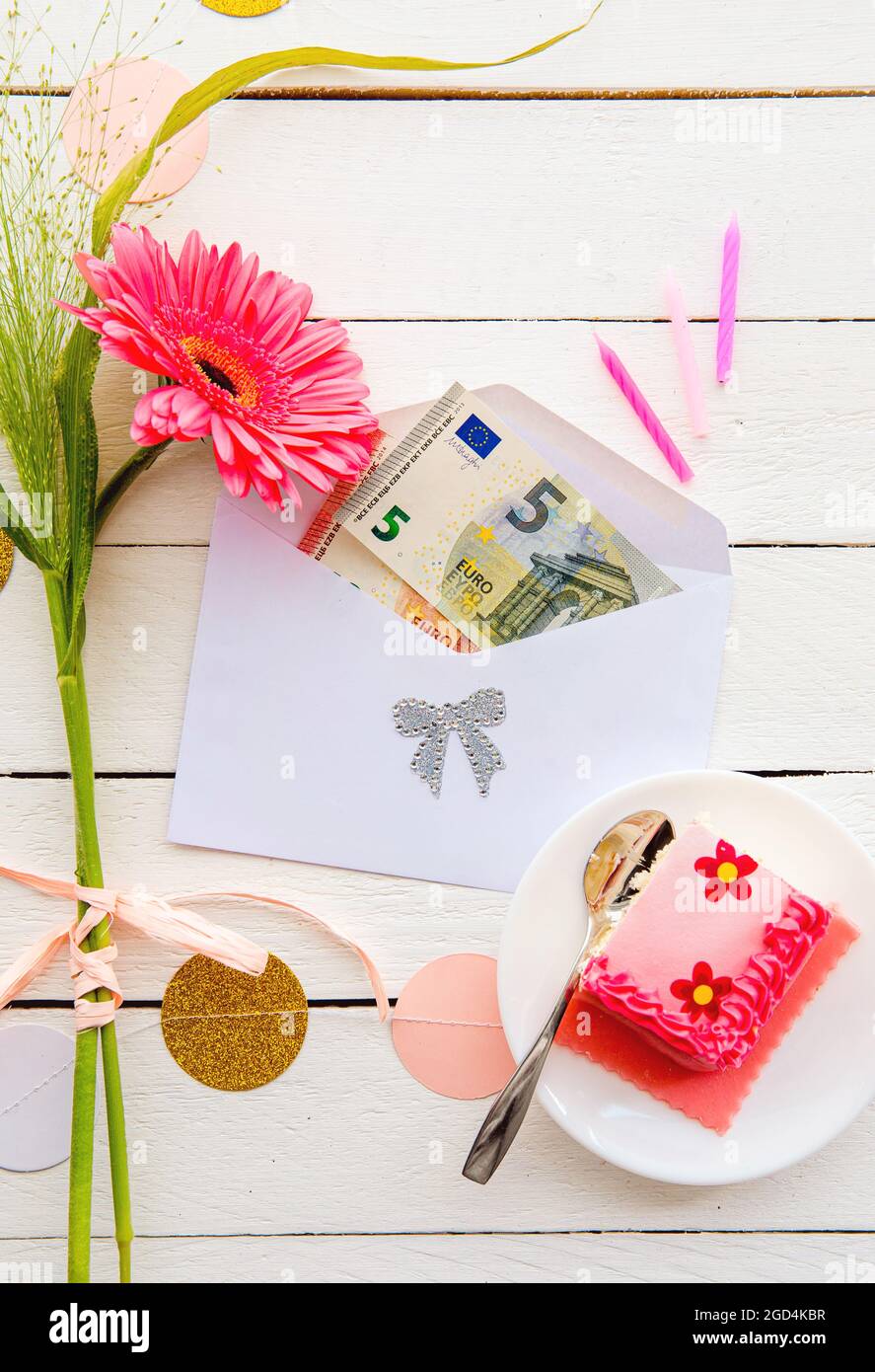 Euro argent comme cadeau d'anniversaire concept. Billets de banque euro à l'intérieur de l'enveloppe, décorés de gâteaux et de fleurs. Banque D'Images