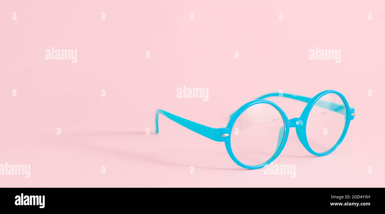 Lunettes bleues sur fond rose pastel avec espace de copie, bannière Banque D'Images