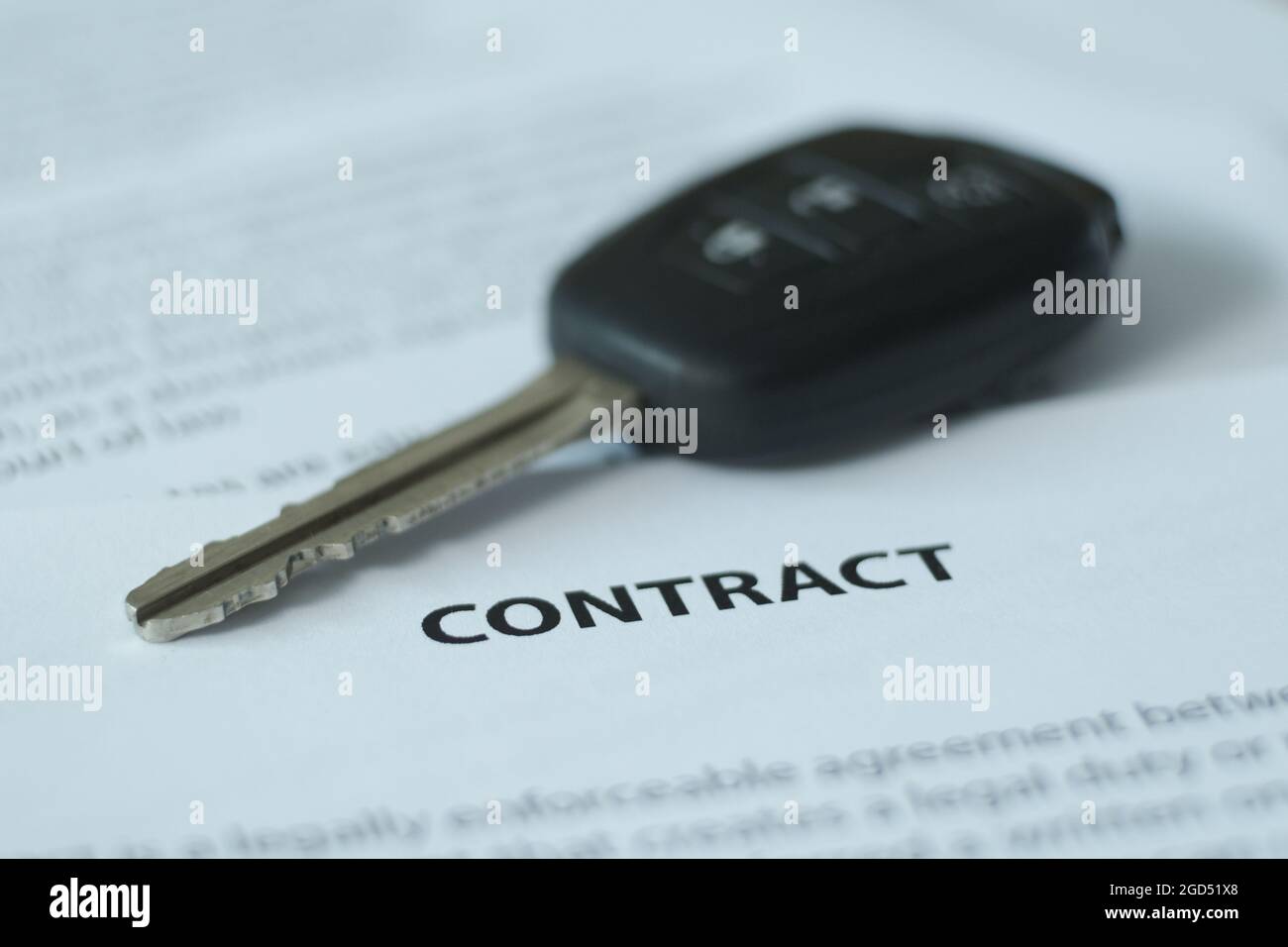 Il y a un contrat et des clés de voiture sur la table, l'accent est mis sur le nom du document et les clés. Image floue. Banque D'Images