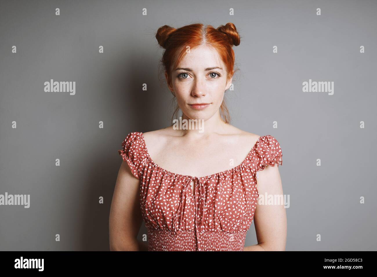 portrait intérieur de jeune femme souriante avec des petits pains aux cheveux rouges Banque D'Images