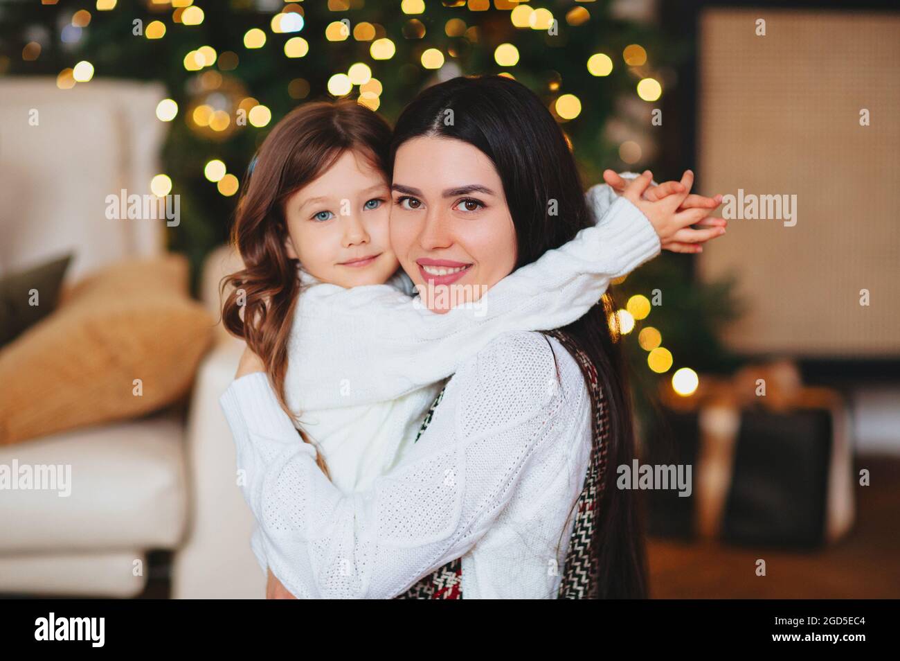 Bonne petite fille ludique fille jouant avec la mère positive, passant du temps ensemble pendant les vacances de Noël à la maison, maman et enfant s'amuser Banque D'Images