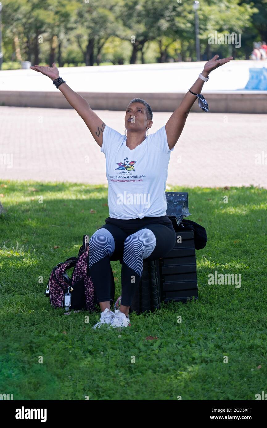Un instructeur de yoga et de bien-être d'âge moyen levant les bras dans une classe à Flushing Meadows Corona Park dans le Queens. Banque D'Images