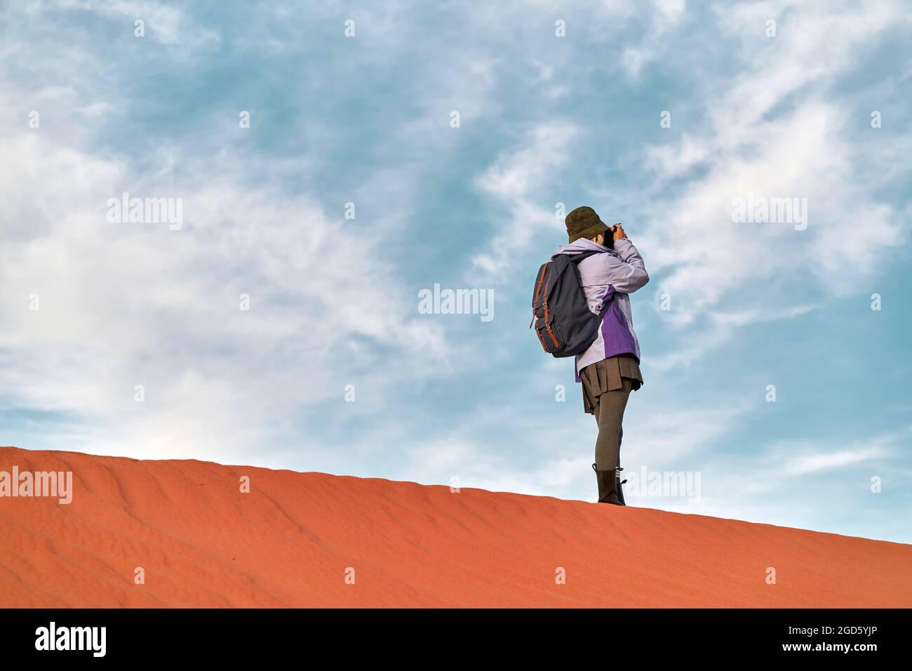 photographe asiatique debout au-dessus d'une dune de sable prenant une photo Banque D'Images
