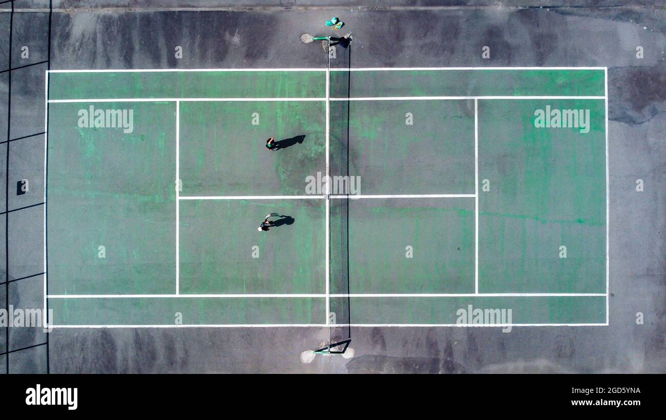 Court de tennis vu avec un drone à 180 degrés, avec la peinture verte portée par le temps et la texture du sol dépassant, dans l'image l'ombre du n Banque D'Images