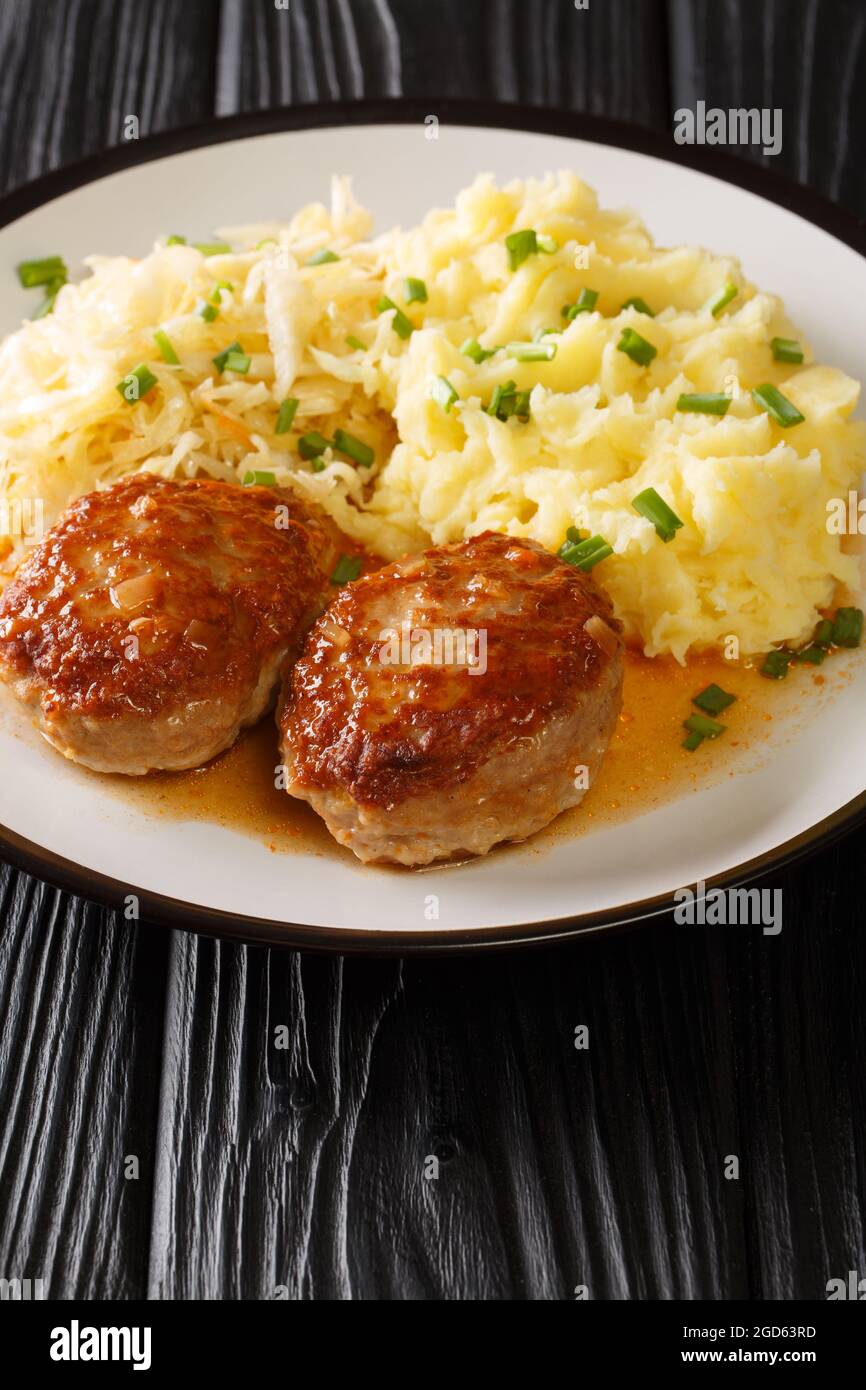 Viandes de porc norvégiennes chaudes Medisterkaker servi avec une purée de pommes de terre et de choucroute dans une assiette sur la table. Verticale Banque D'Images