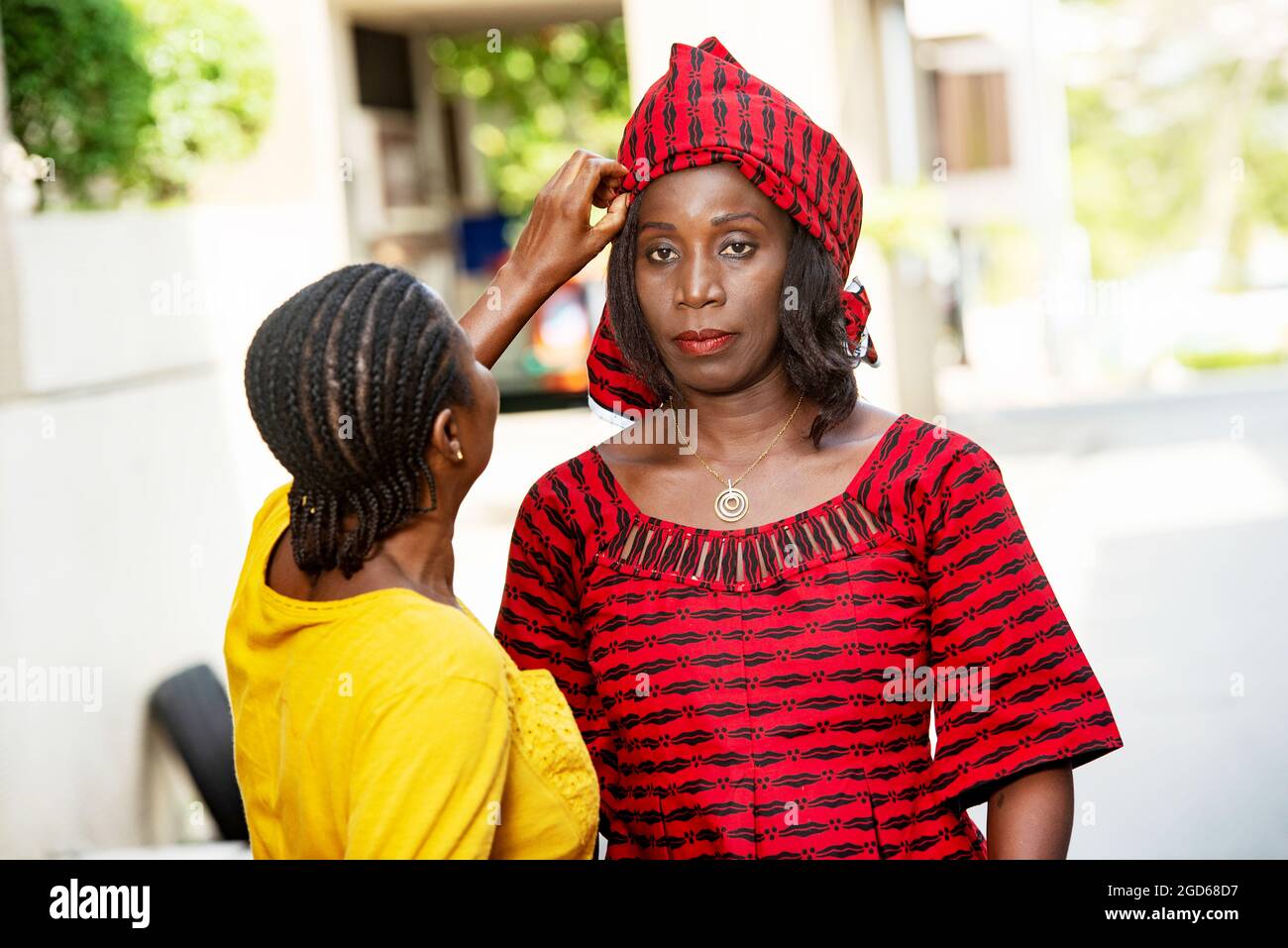 femme africaine mûre debout à l'extérieur regardant la caméra tandis que sa sœur ajuste son foulard. Banque D'Images