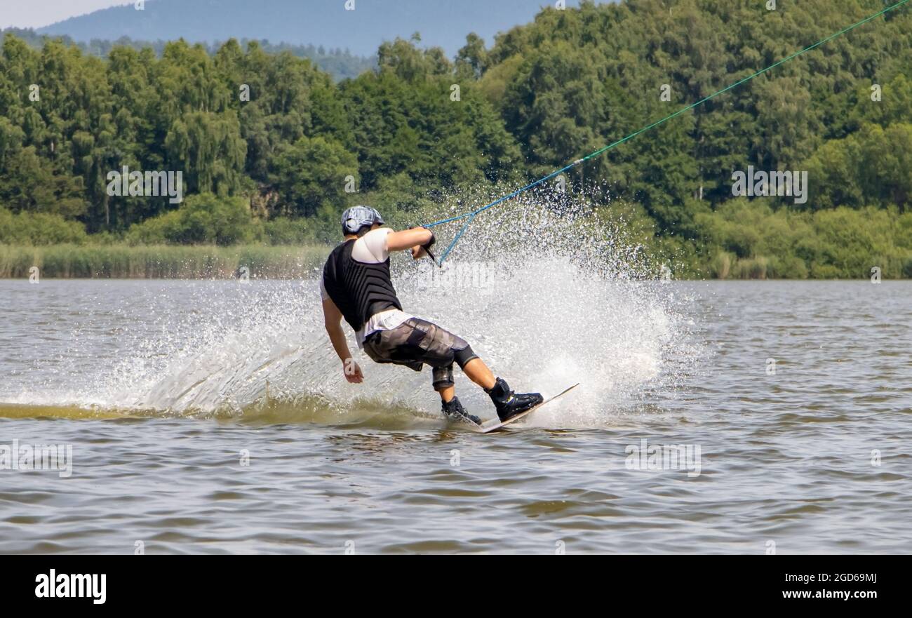 Un homme à bord d'une planche de surf. Un surfeur est tiré sur un remorquage d'eau sur le lac. Banque D'Images