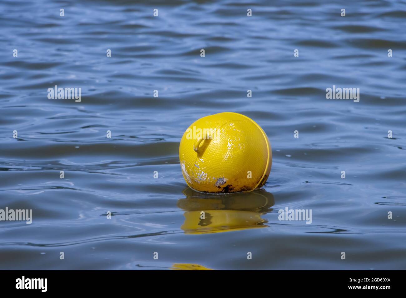 Une bouée jaune flotte sur une surface d'eau dans un lac. Banque D'Images