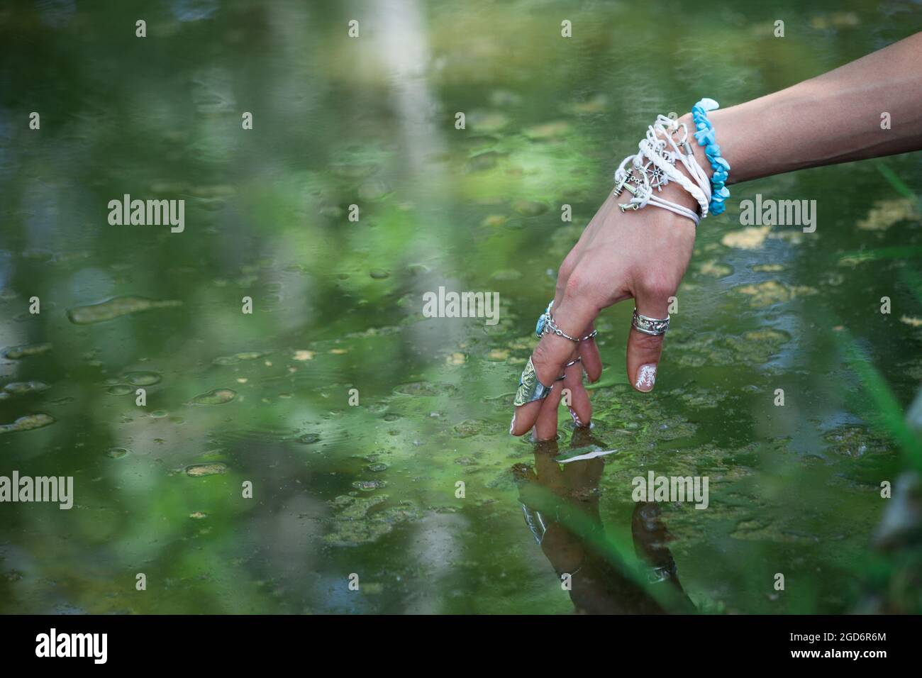 femme main touchant l'eau avec des bagues de style boho et des bracelets en Banque D'Images