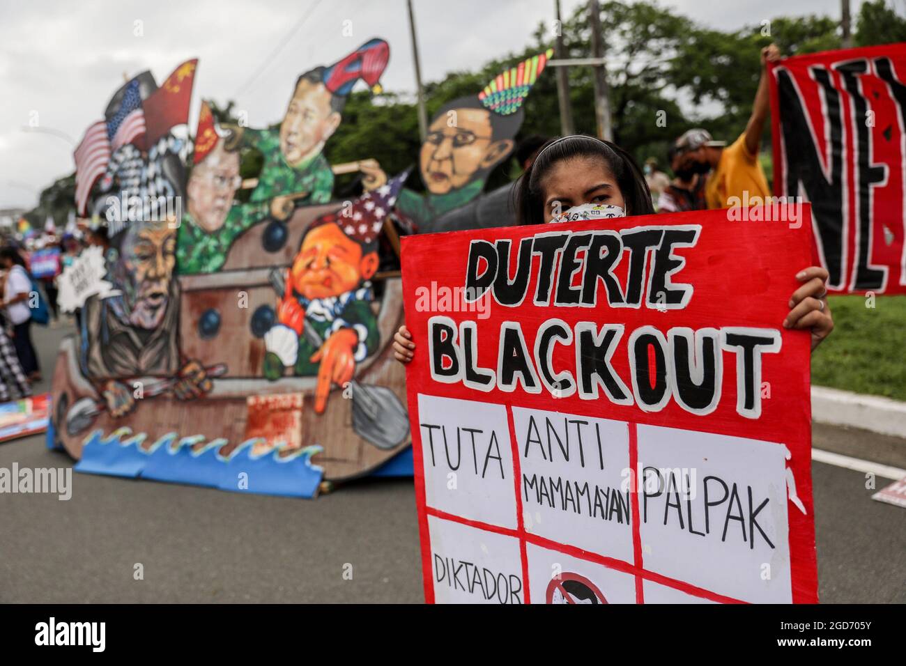 Un manifestant porte un masque de protection avec un signe avant le dernier discours sur l'état de la nation du président Rodrigo Duterte à Quezon City, dans le Grand Manille. Des milliers de manifestants de gauche se sont rassemblés et ont défilé vers le Congrès philippin, où Duterte a prononcé son dernier discours sur l'état de la nation, en liquidant son mandat de six ans au milieu de critiques telles que des violations présumées des droits de l'homme, Mauvaise gestion de la pandémie du coronavirus et inaction face au comportement agressif de la Chine dans la mer de Chine méridionale contestée. Philippines. Banque D'Images