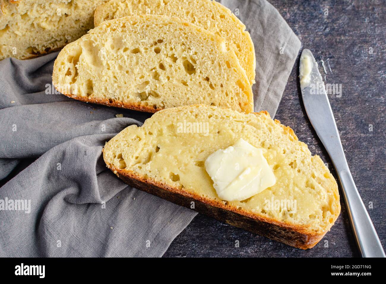 Tranches de pain français avec une Pat de beurre : tranche de pain français beurrée avec un couteau de table et une serviette en tissu Banque D'Images