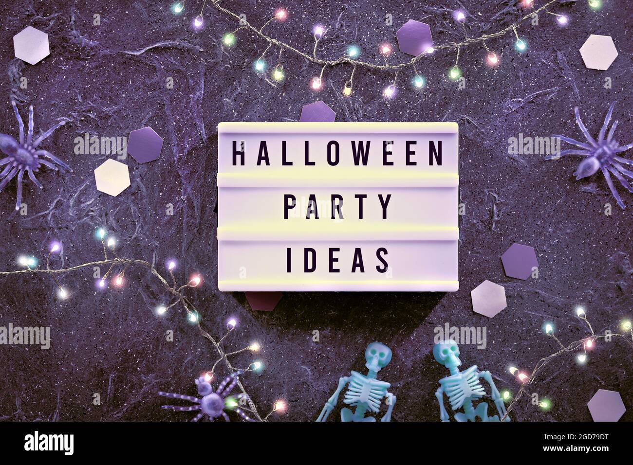 Décoration d'Halloween et idées de fête d'Halloween écrites sur la zone de texte. Arrière-plan minimal pour Halloween avec squelettes vert pâle et araignées violettes. Sombre Banque D'Images