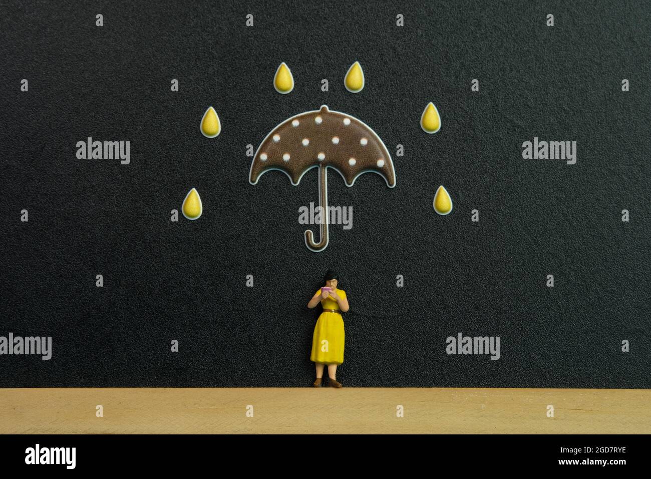 Photographie miniature de personnage de jouet de personnes. Une fille lisant un livre au-dessus d'un tableau noir ou d'un tableau noir avec une étiquette de droplet et de parapluie. Photo d'image Banque D'Images