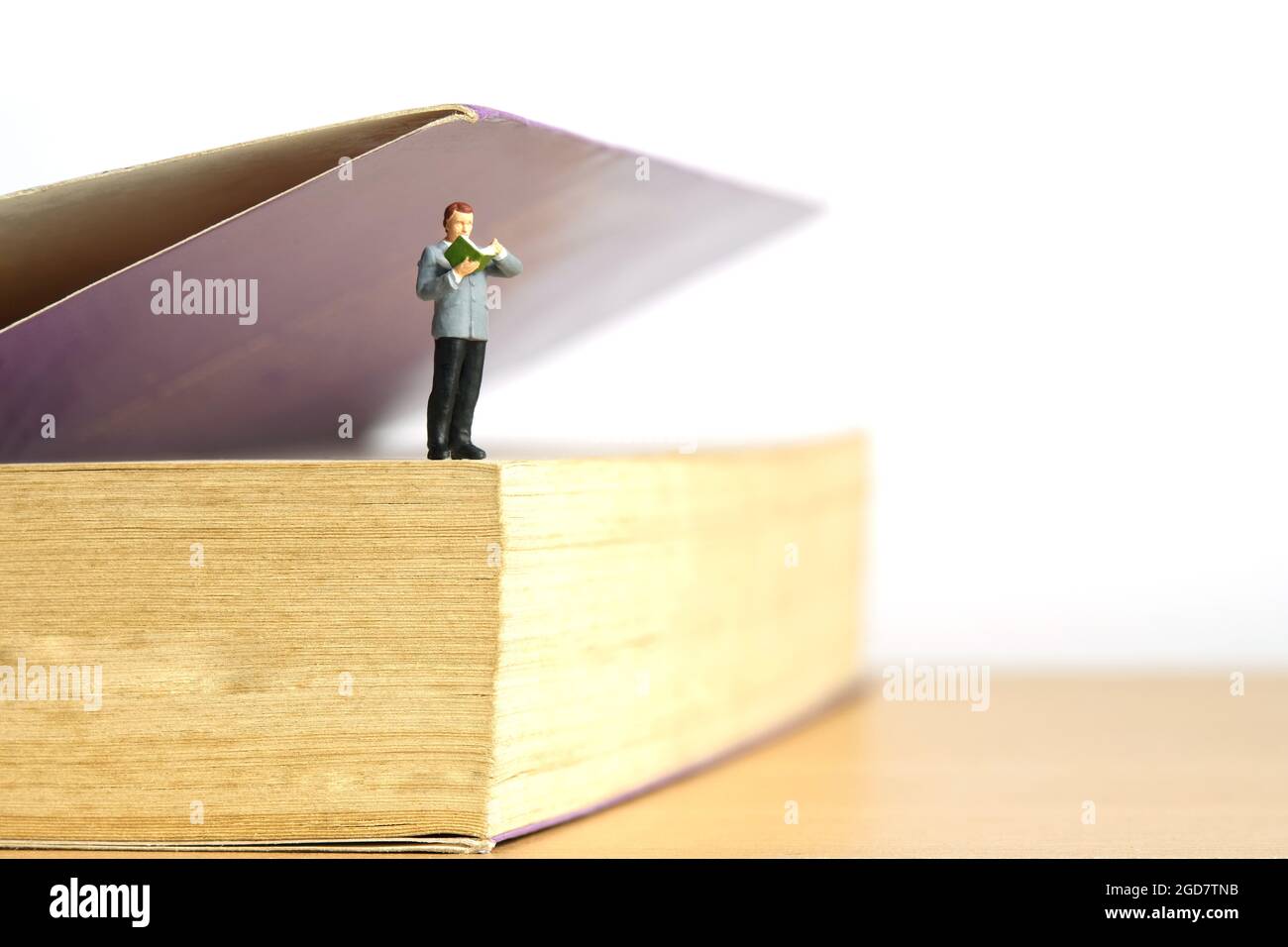 Photographie miniature de personnage de jouet de personnes. Un homme se tenant au-dessus du livre ouvert pendant la lecture. Photo d'image Banque D'Images