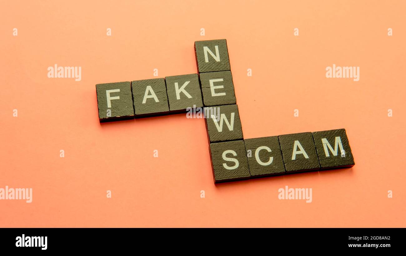Un groupe de mosaïque scarable formant le mot escroquerie fausses nouvelles. Mise au point sélective sur les tuiles isolées sur fond rose Banque D'Images
