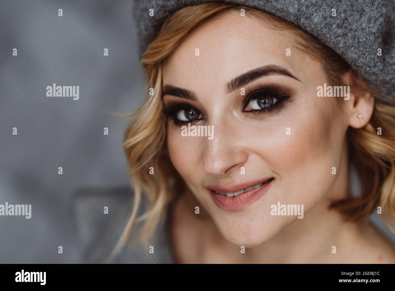 Portrait d'une belle femme blonde avec maquillage fumé pour les yeux dans un béret gris. Mise au point sélective douce. Banque D'Images