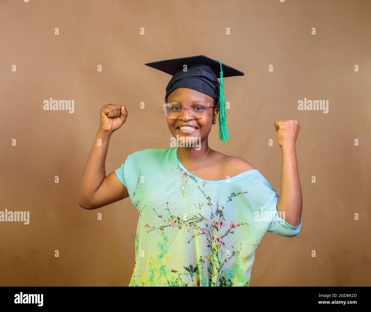 Une femme africaine nigériane ou diplômée, portant un chapeau de graduation et des lunettes, exprimant la joie due au succès de son école, de son éducation et de sa carrière Banque D'Images