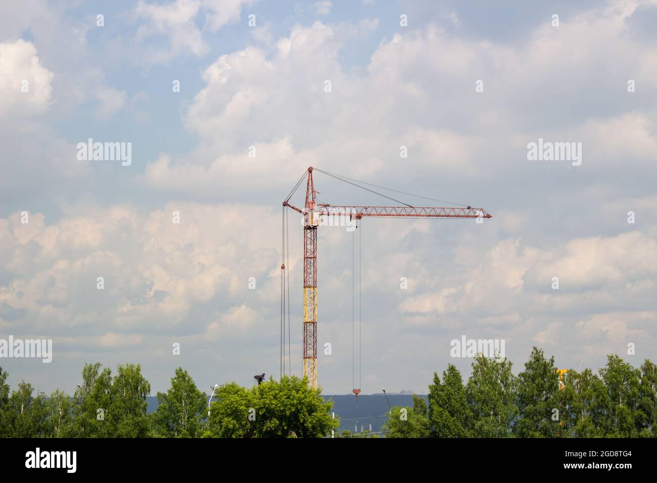 Un chantier de construction avec un bloc en hauteur en construction dans un environnement urbain dominé par une grande grue industrielle, silhoueté contre un bea Banque D'Images