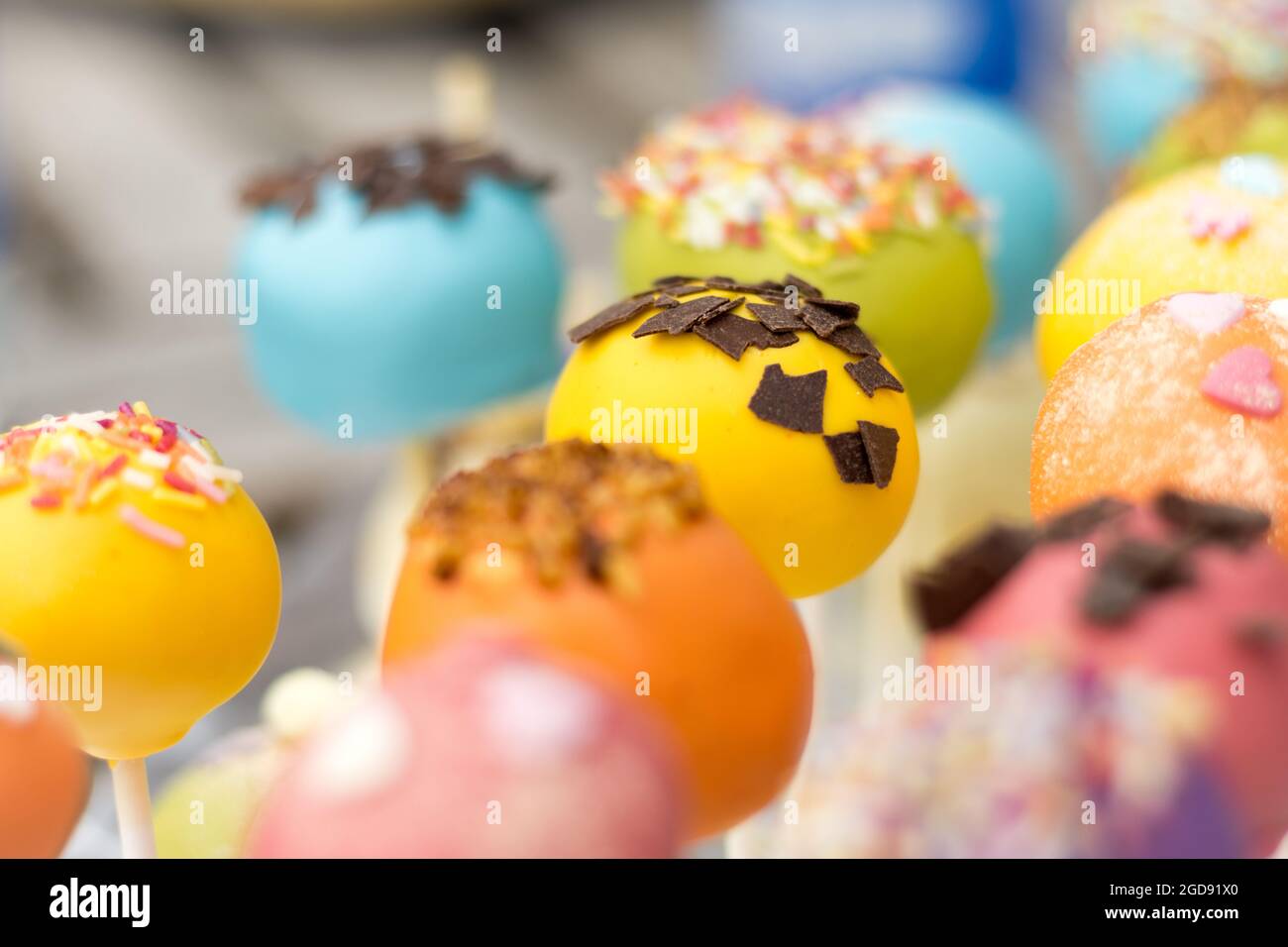 Une délicieuse exposition de gâteaux colorés ornés de pépites et de flocons de chocolat, mettant en valeur des teintes vibrantes et des décorations complexes. Banque D'Images