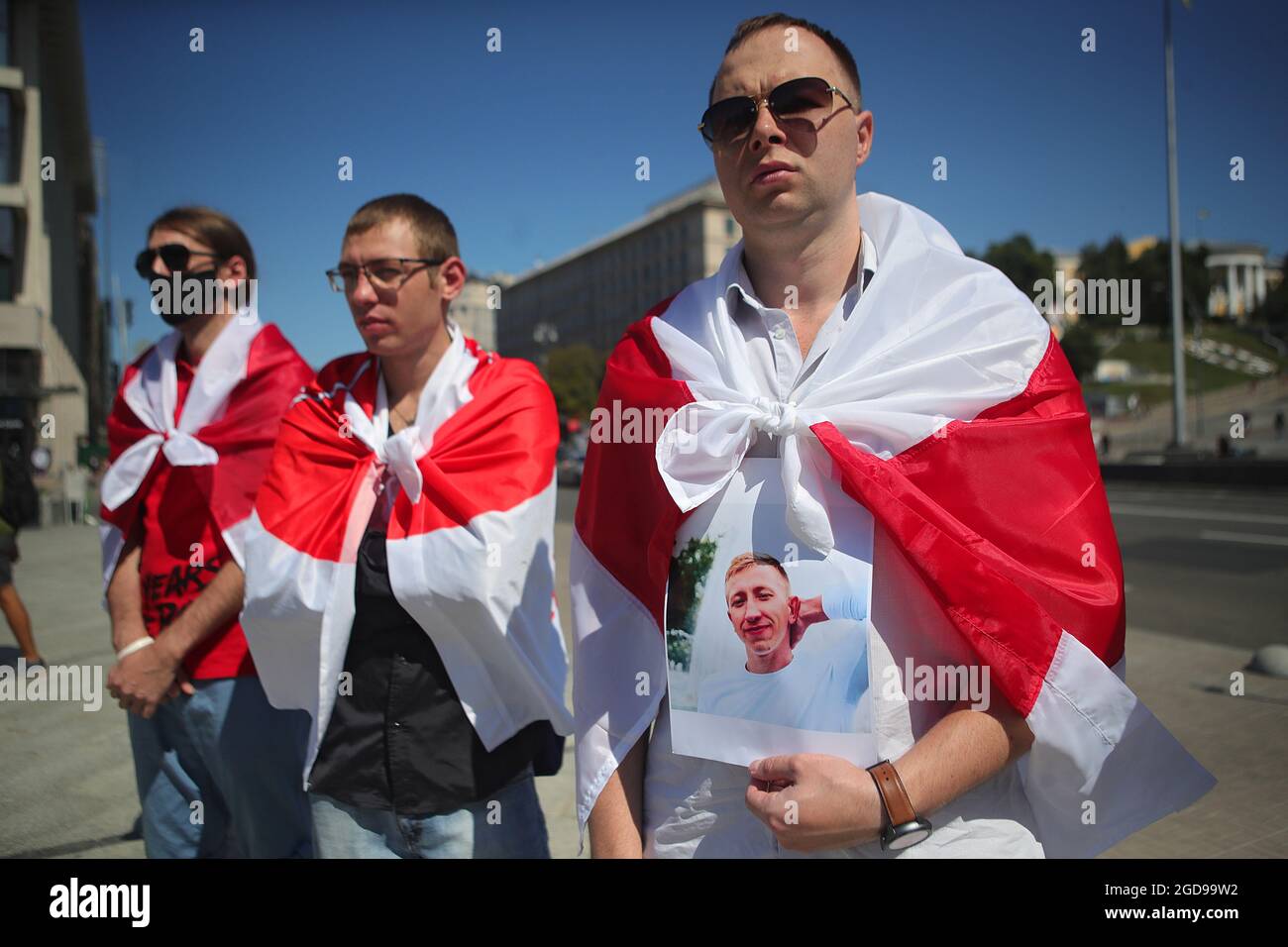 Non exclusif: KIEV, UKRAINE - AOÛT 8 2021 - un activiste enveloppé dans un drapeau biélorusse historique tient le portrait de la Maison biélorusse en Ukraine N Banque D'Images