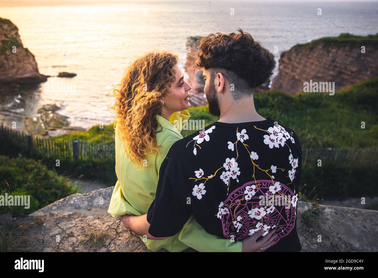 Les jeunes couples hétérosexuels s'embrassent au sommet d'une falaise près de l'océan. Banque D'Images