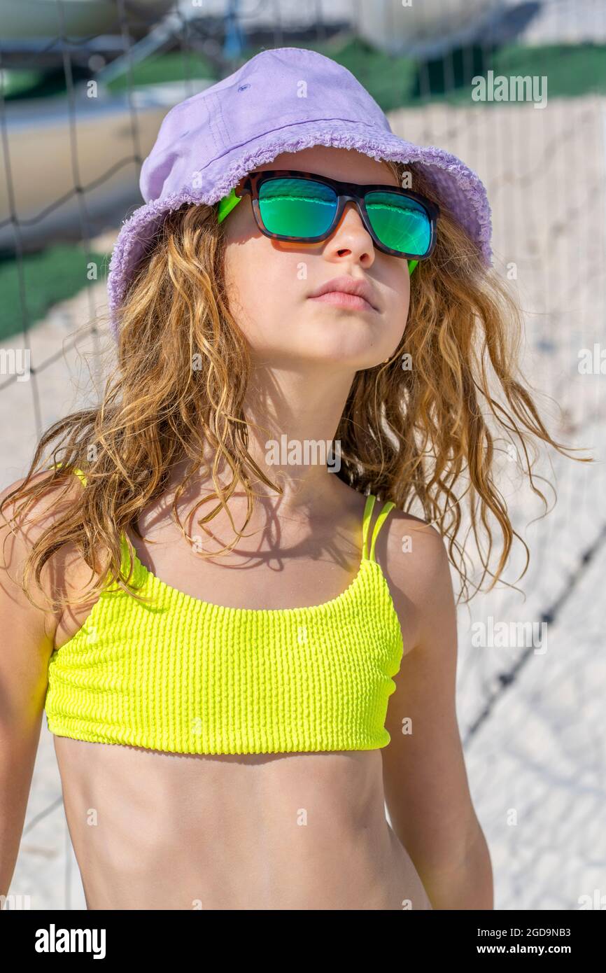 Portrait d'une jeune fille magnifique modèle avec chapeau et lunettes de  soleil posant sur la plage. Porter un maillot de bain de bikini jaune vif.  Jour d'été, sable blanc. Photo de haute