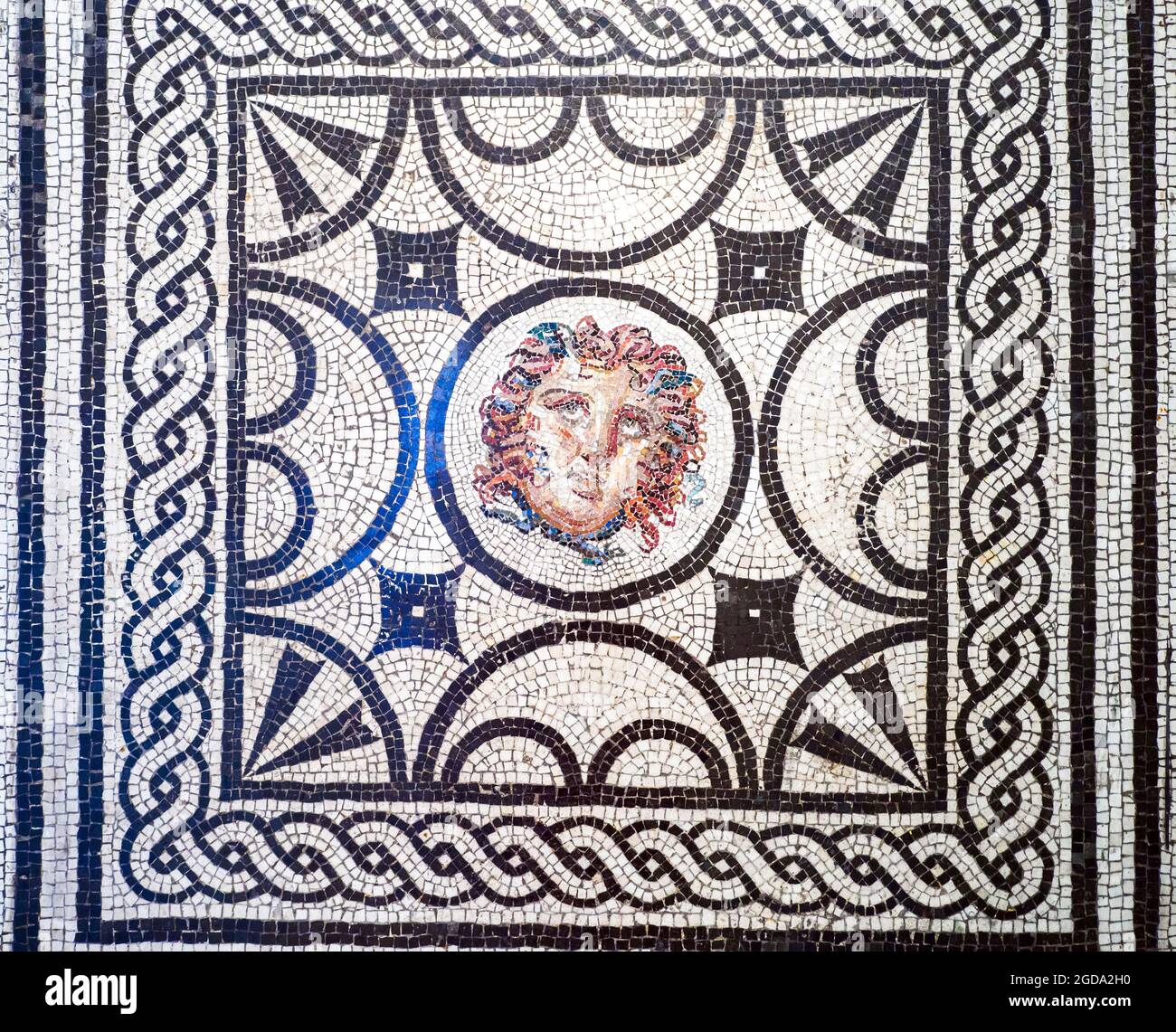 Tête de Medusa mosaïque noire et blanche emblème en opus vermiculatum fabriqué à partir de tesserae polychrome. Le tondo au centre montre la tête de Medusa, inséré dans un panneau dont les côtés sont décorés de quatre motifs pelta alternés et de deux demi-cercles avec palmettés dans les coins. Les figures sont enfermées dans un cadre avec un motif entrelacé et deux cadres linéaires Pompéi, Casa delle Vestali (Maison des Vestales) - début du 1er siècle après J.-C. Banque D'Images
