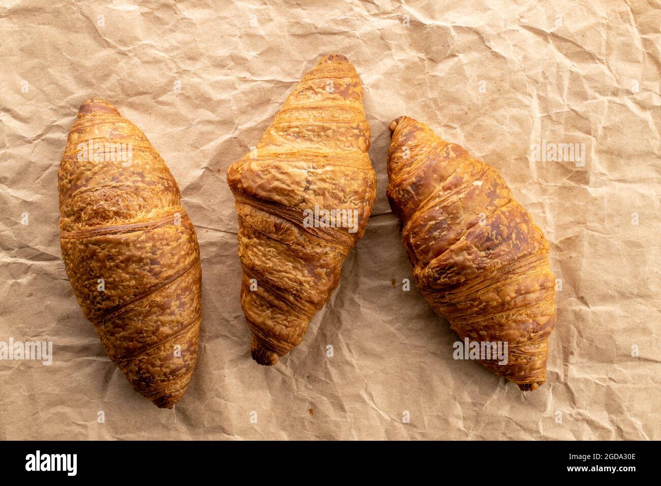 Trois délicieux croissants avec garniture au chocolat sur papier artisanal, gros plan, vue de dessus. Banque D'Images