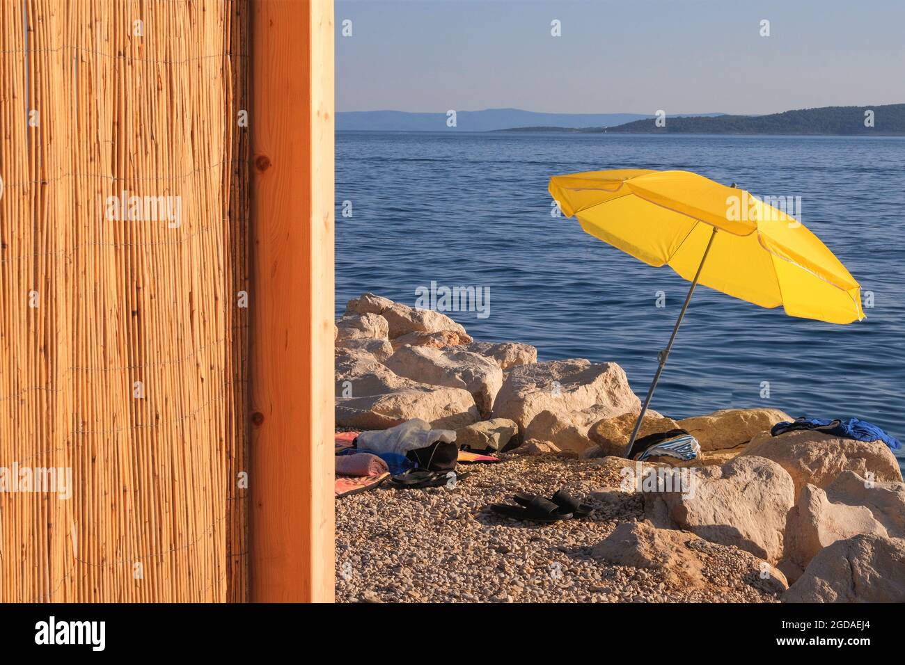 Parasol jaune sur la côte d'été. La plage de la mer avec parasol attend les touristes au coucher du soleil. Concept de vacances d'été heureux. Vue verticale. Banque D'Images