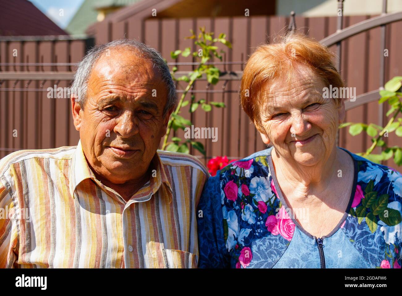 Portrait d'un couple âgé souriant en été. Une bonne paire de personnes âgées, mari et femme, est assise sur le jardin fleuri. homme des années 60 ou 70 et woma Banque D'Images