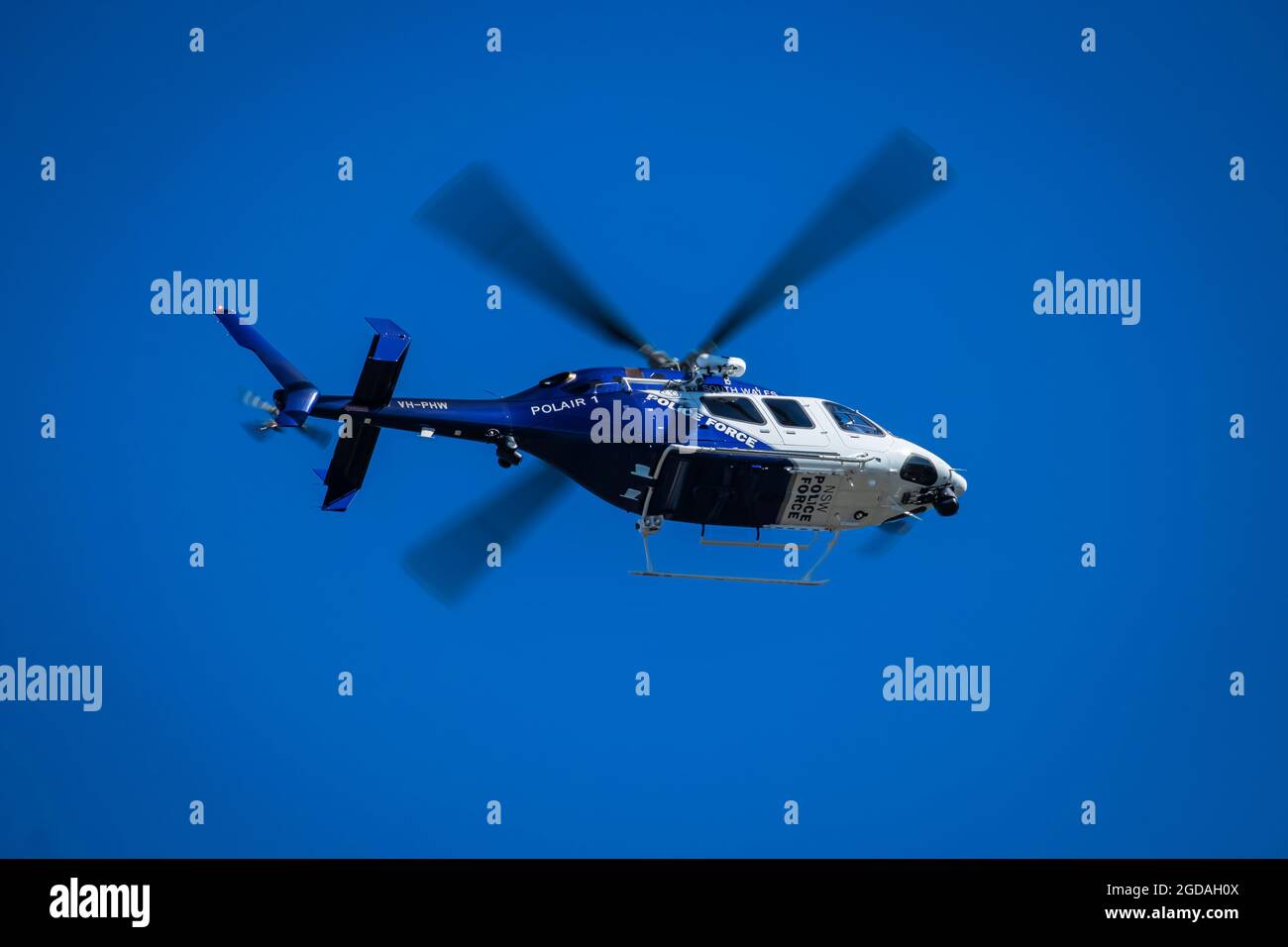 New South Wales police Force, Polair 1, hélicoptère de police volant haut contre un ciel bleu avec des pales de rotor floues de mouvement Banque D'Images