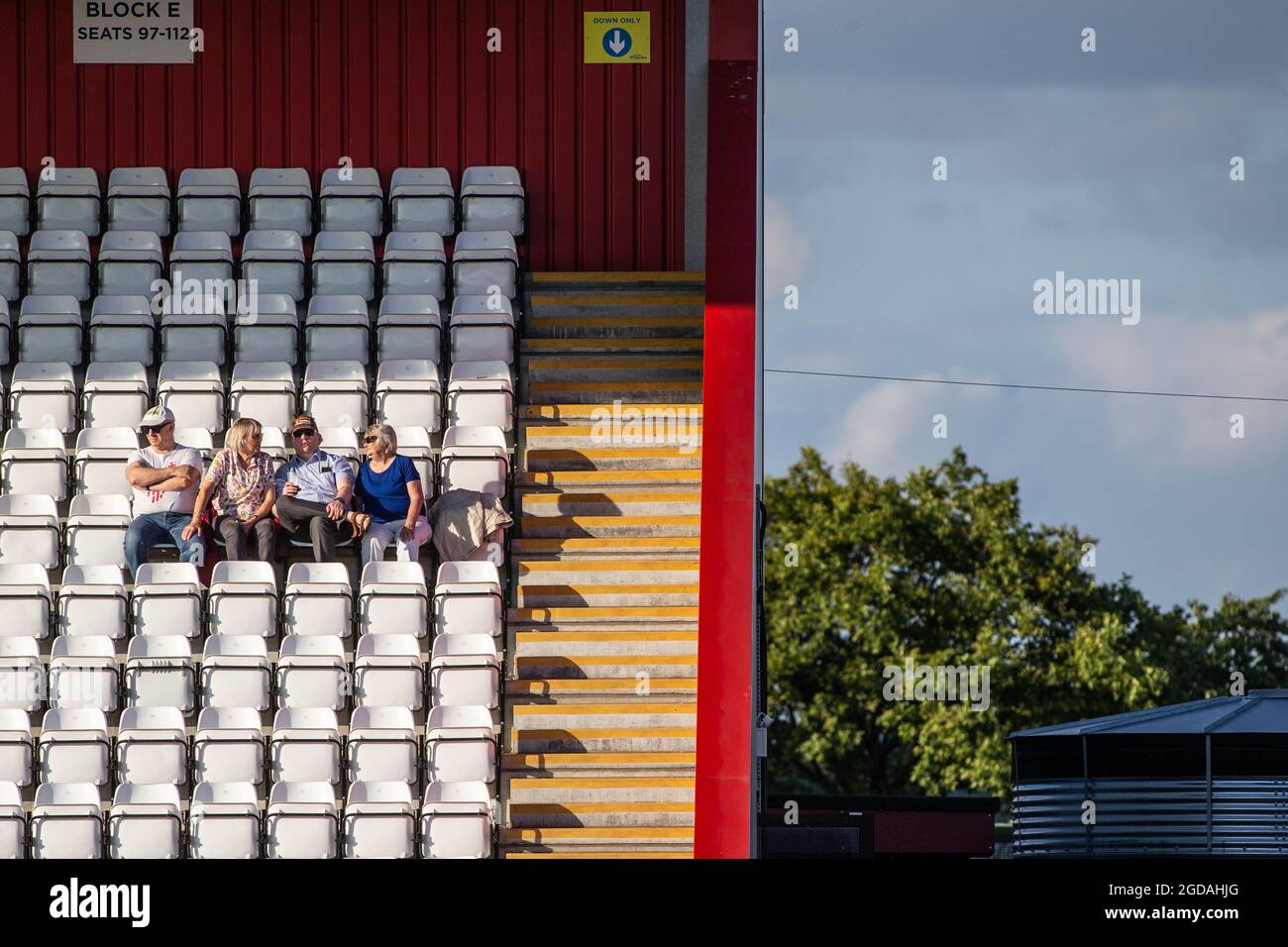 petit groupe de spectateurs assis sur des sièges isolés au stade de football Banque D'Images