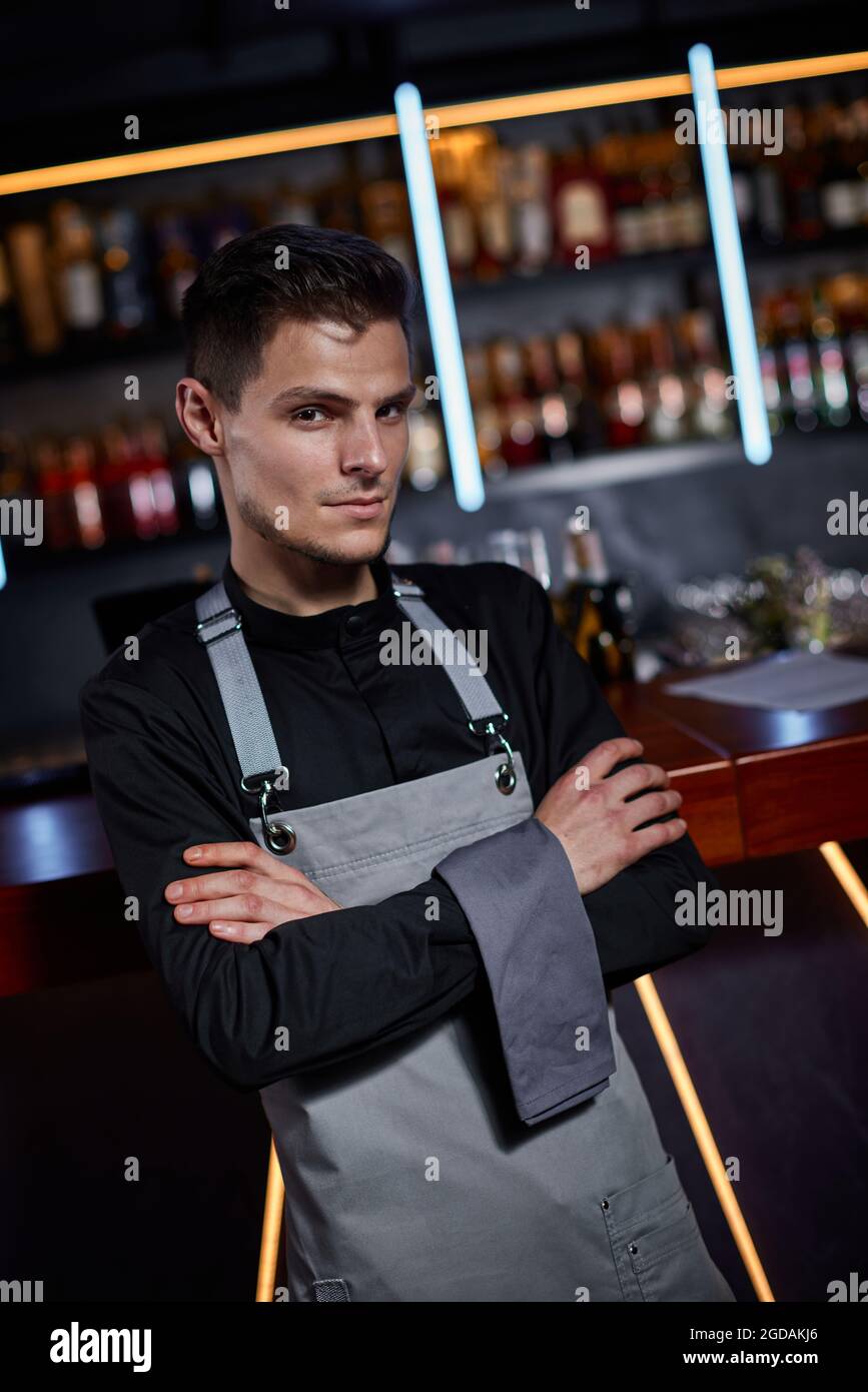 Beau barman en tablier debout au comptoir du bar Banque D'Images